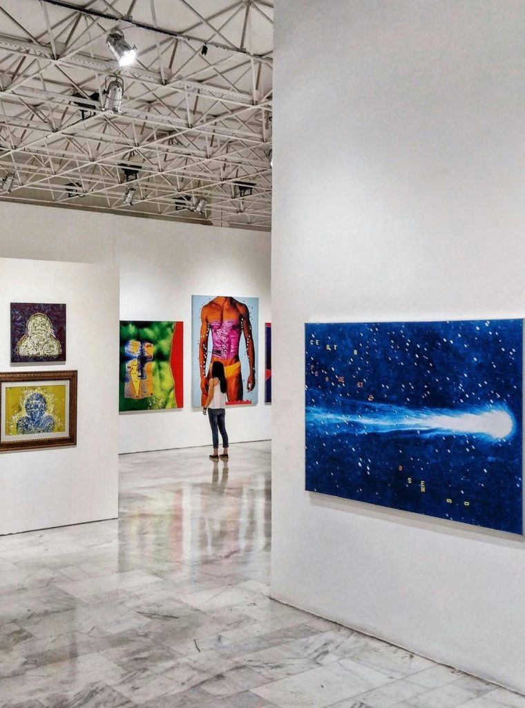 Gallery showcasing diverse contemporary art pieces with an observer in view.